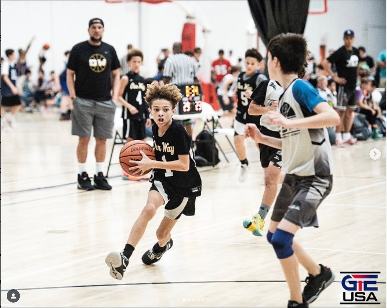 OW player in a black jersey pushing the ball upcourt with two opponents nearby