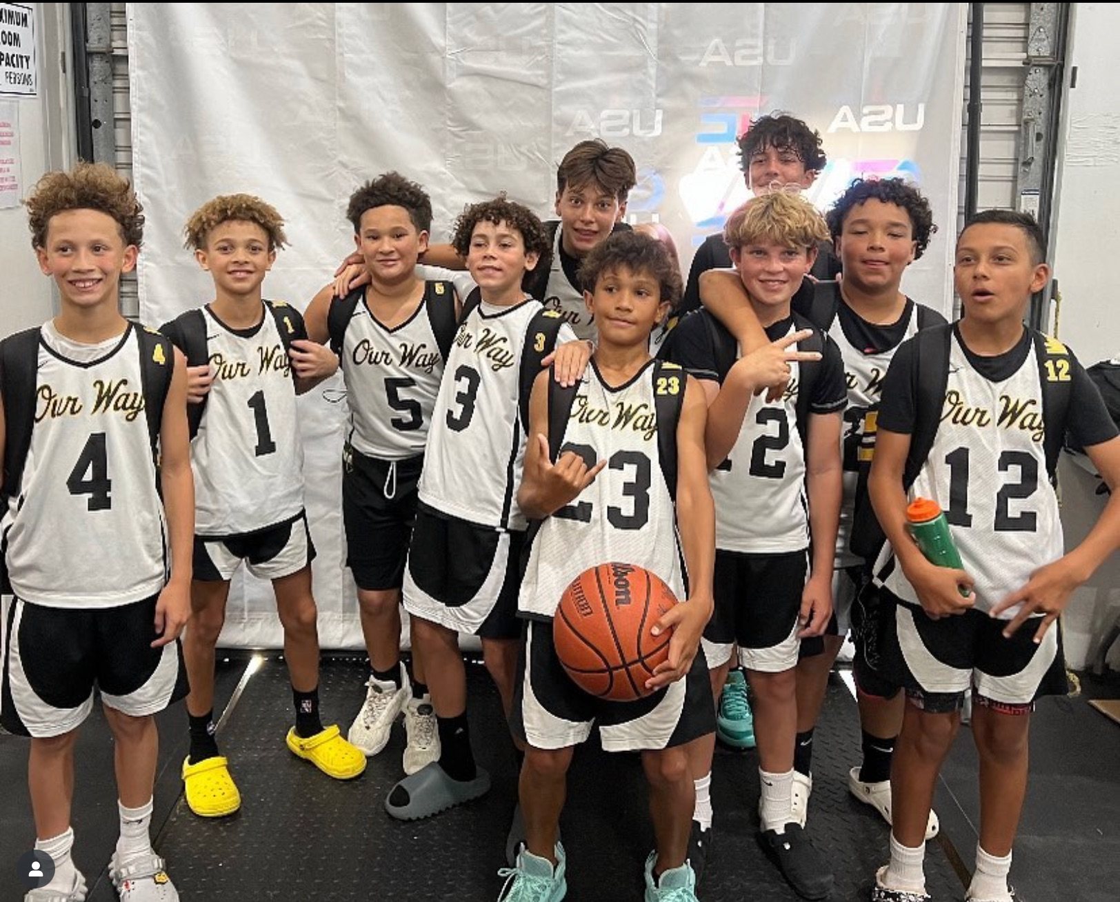 OW players posed together in front of a tournament backdrop, one holding a basketball