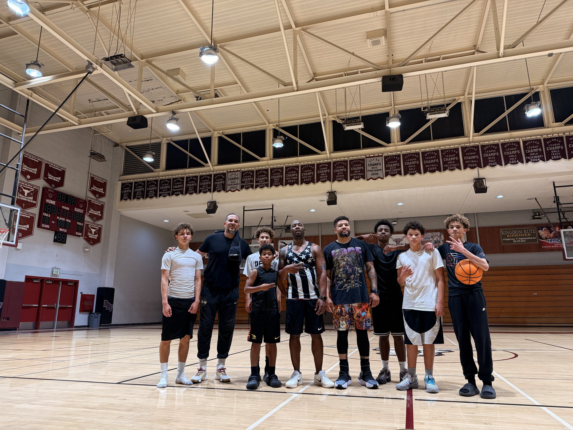 OW players and two coaches standing together at midcourt in a high school gym